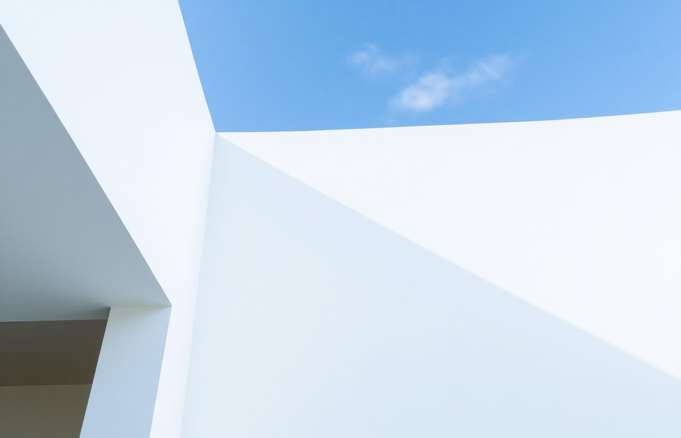 Minimal white architectural forms against a blue sky